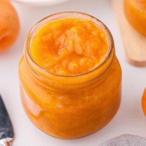 close-up of apricot preserves in a jar on white table