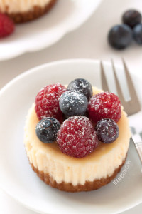 mini gluten-free cheesecake topped with fresh berries on a white plate
