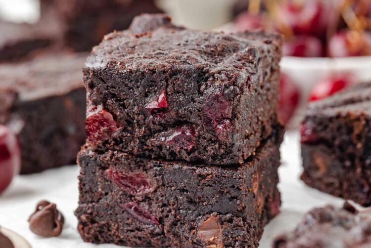 stack of 2 cherry brownies on a white table with more in the background