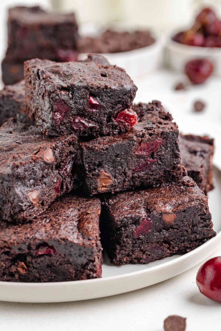 cherry brownies stacked on a white plate on a white table