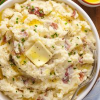 Red-skinned mashed potatoes in bowl with butter on top