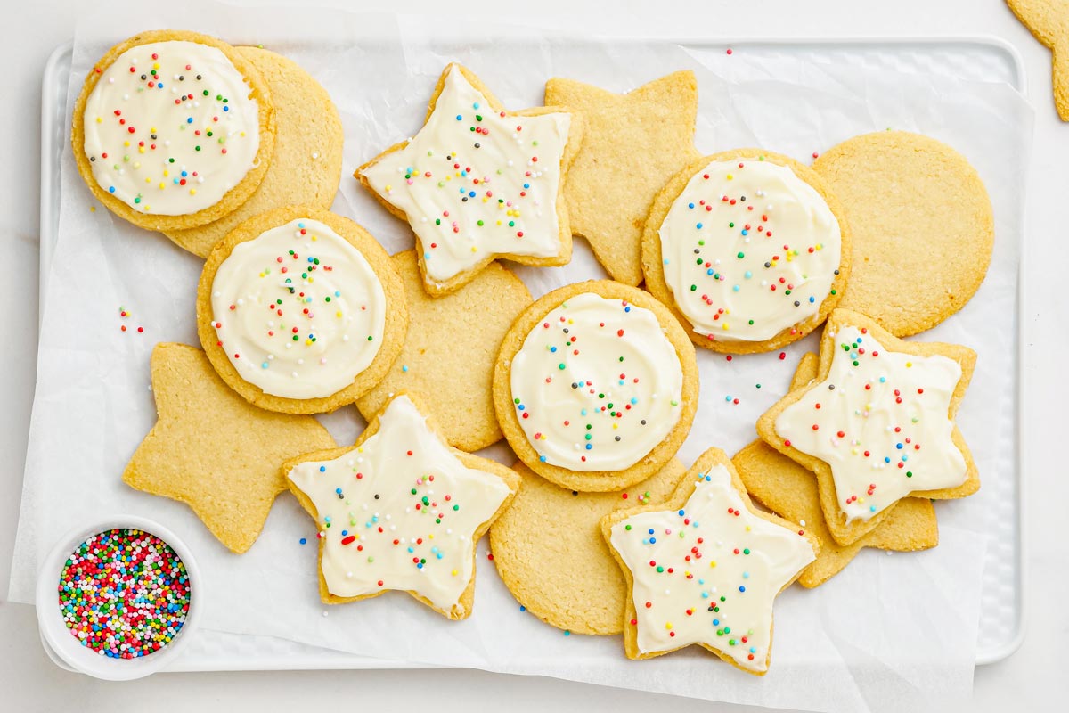 A white tray with white parchment paper and almond flour sugar cookies.