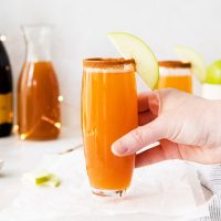 hand on glass of apple cider mimosas