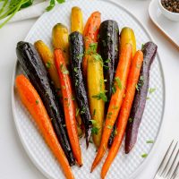 image of roasted rainbow carrots that are yellow, orange and deep purple on a serving plate