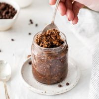 spoon in a jar of ready chocolate protein overnight oats