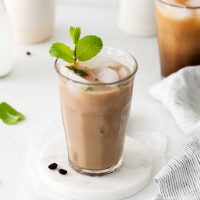 photo of a glass of an espresso mojito over ice garnished with a sprig of fresh mint