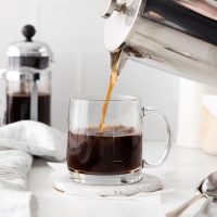 photo showing a stainless steel French press pouring cold brew into a glass mug