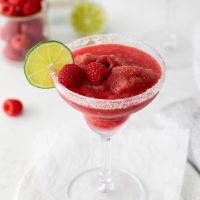 margarita glass with raspberry margarita and lime wedge