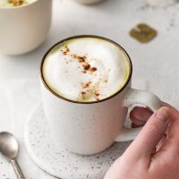 hand on mug of chai matcha latte