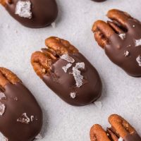 pecans covered in chocolate with flaky sea salt on top