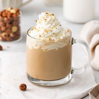 image of hazelnut latte topped with whipped cream and bits of hazelnuts