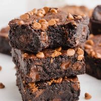 side view photo of a stack of olive oil brownies topped with chocolate chips and a bite taken out of one