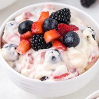 top view photo of red white and blue cheesecake salad with a smooth white cheesecake filling in a bowl with fresh fruit blueberries and strawberries mixed in the filling and garnished on top