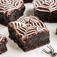 close up image of a chocolatey brownie with white chocolate webs on top to make gluten-free spiderweb brownies, perfect for Halloween
