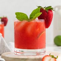 image showing an elegantly red strawberry mule garnished with a fresh strawberry and mint sprig