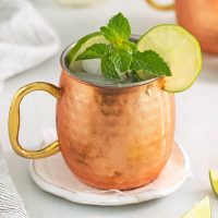 image of a cooper mug with a virgin Moscow mule garnished with a lime wheel and a sprig of mint on a white coaster