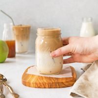 image of a hand reaching for a jar of apple crisp oat milk macchiato