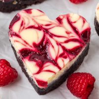 Photo of a heart-shaped brownie with a swirled cheesecake batter and a simple raspberry sauce.