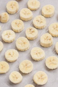 Photo of sliced bananas on parchment paper to show how to freeze banana slices.