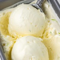 Close-up photo of a pan of lime ice cream with two scoops being rolled into round portions