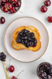 Overhead shot of a white plate with toast topped with homemade cherry preserves