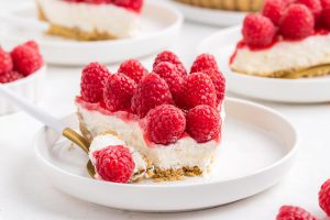 a slice of raspberry tart with a fork holding a bite-size piece on the side