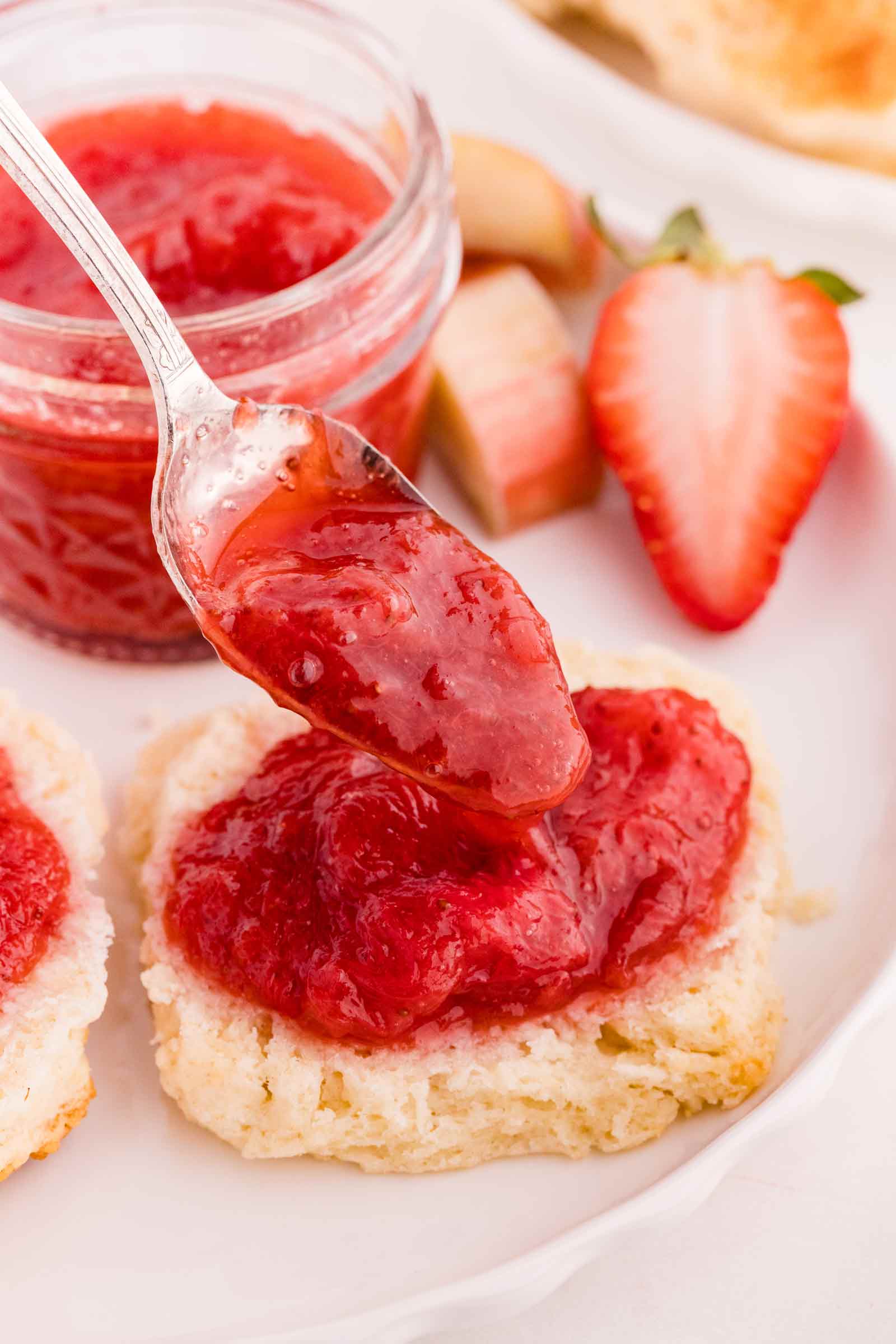 a spoon spooning jam onto a biscuit