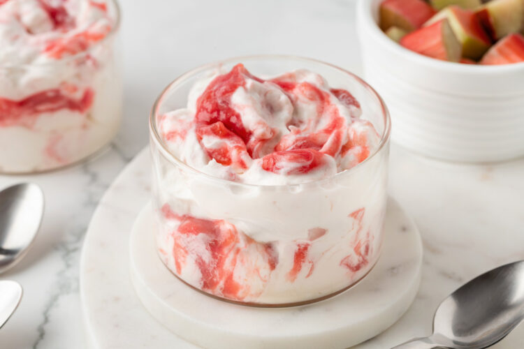 close-up of rhubarb fool on a white table with a spoon in the background