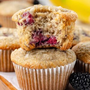 2 banana blackberry muffins stacked on a table