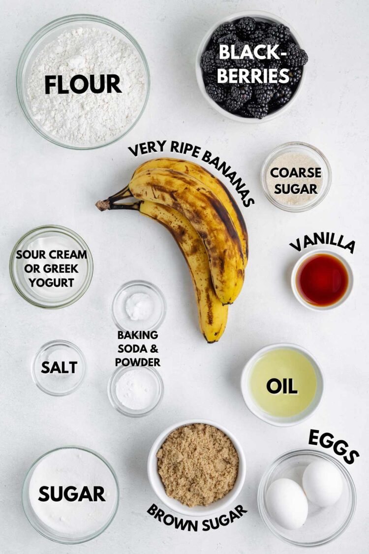 ingredients laid out to make banana blackberry muffins on a white table