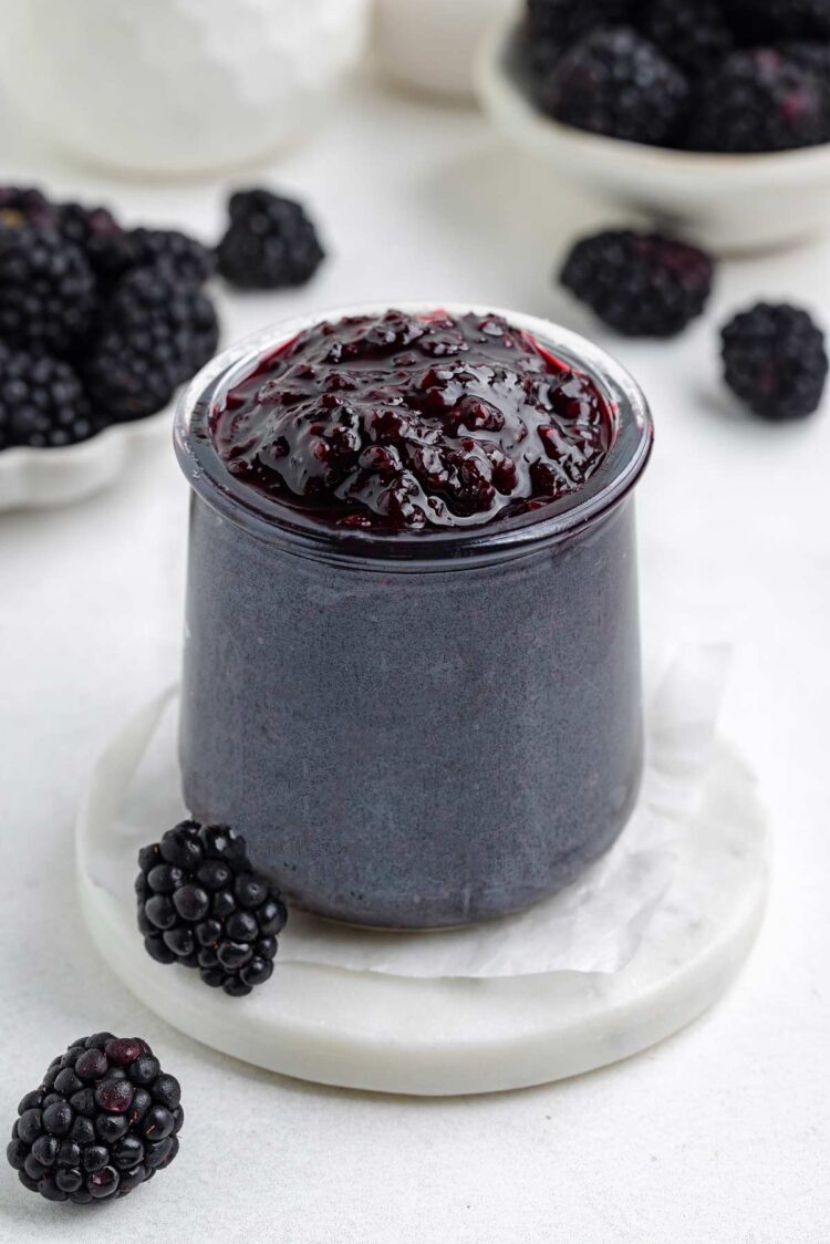 jar filled with blackberry jam on a white table