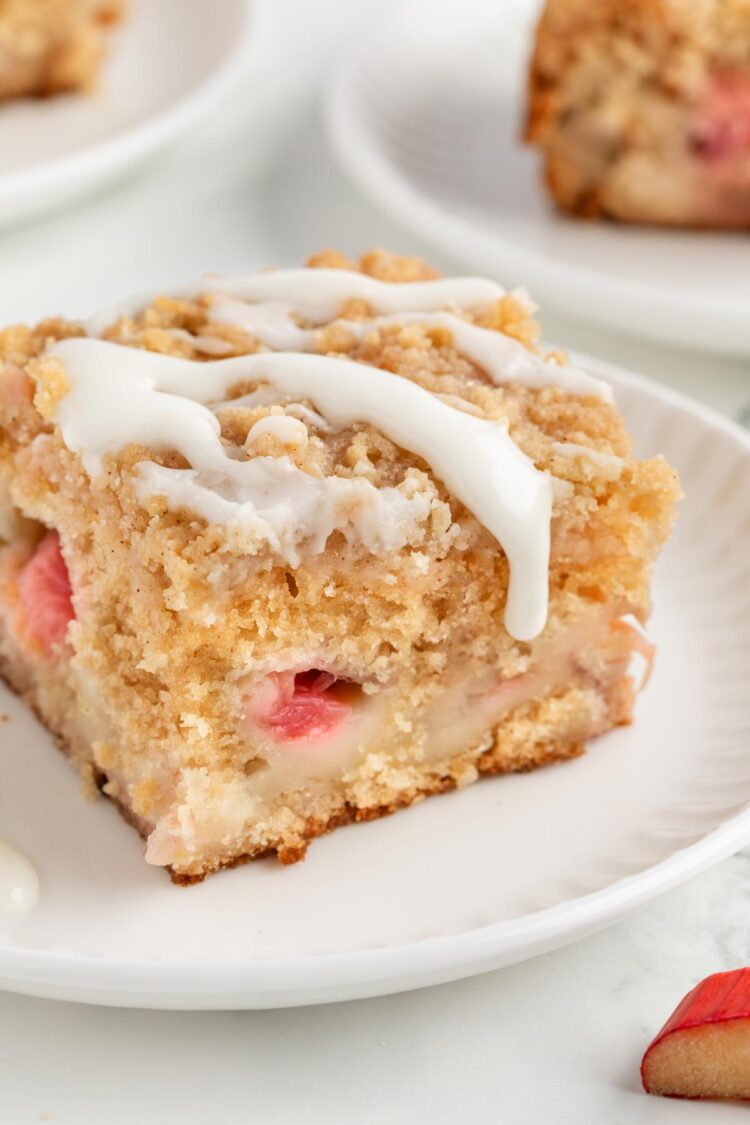 slice of rhubarb cake on a white plate with glaze on top