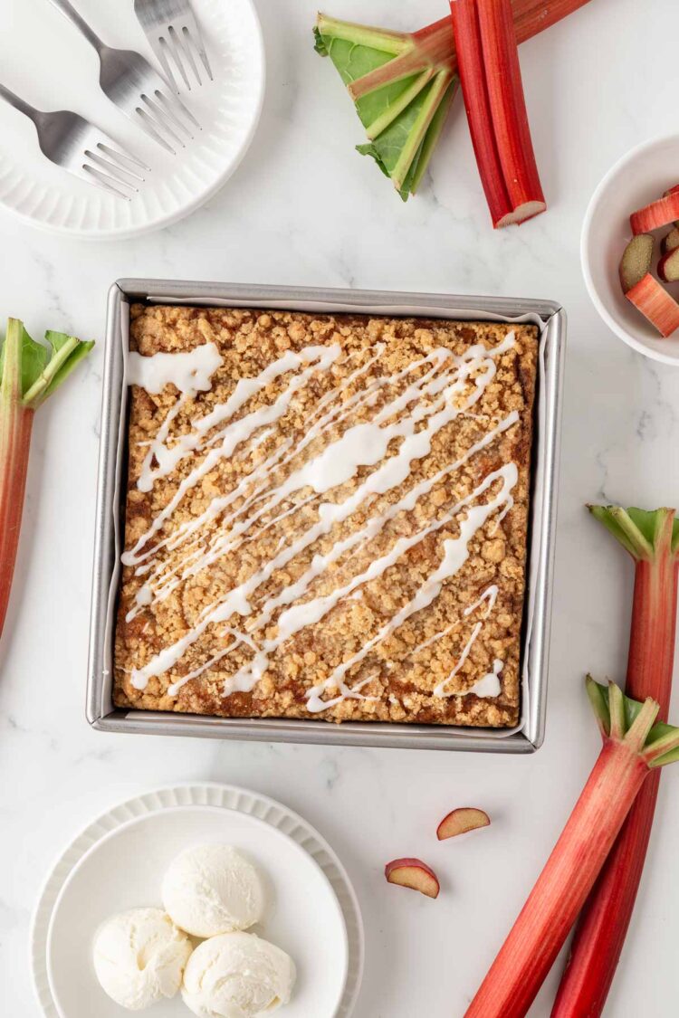 the baked rhubarb cake in its pan with rhubarb in the background