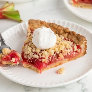 slice of rhubarb tart on white plate with a fork digging into it