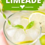 pin image for basil limeade showing a hand holding a glass with basil leaves and ice in it