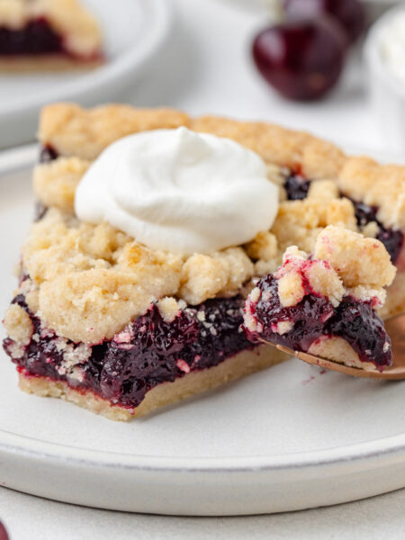 fork digging into a slice of cherry tart on a white plate