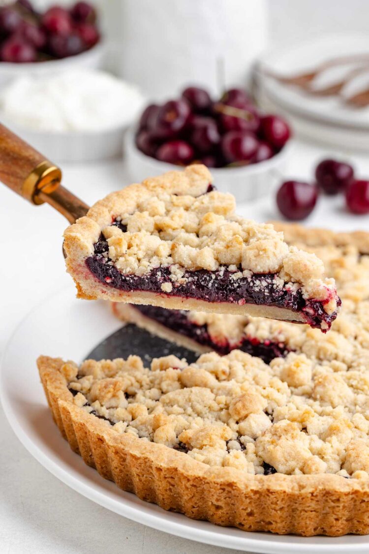 a slice of cherry tart being lifted with a cake server