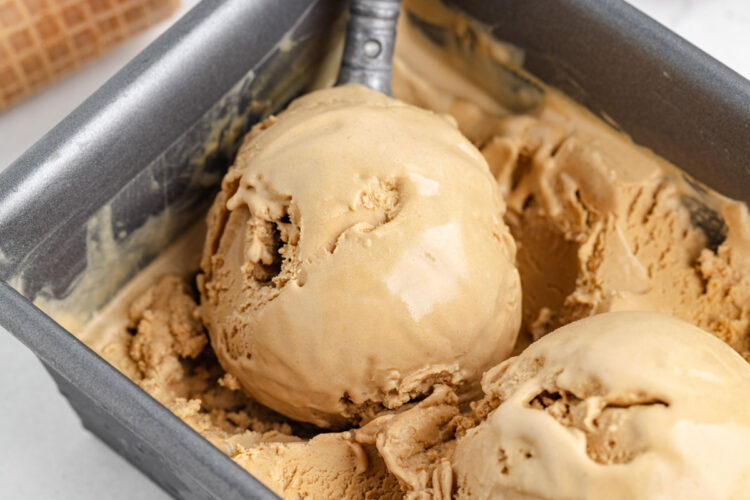 close-up of an ice cream scoop scooping a scoop of butterscotch ice cream
