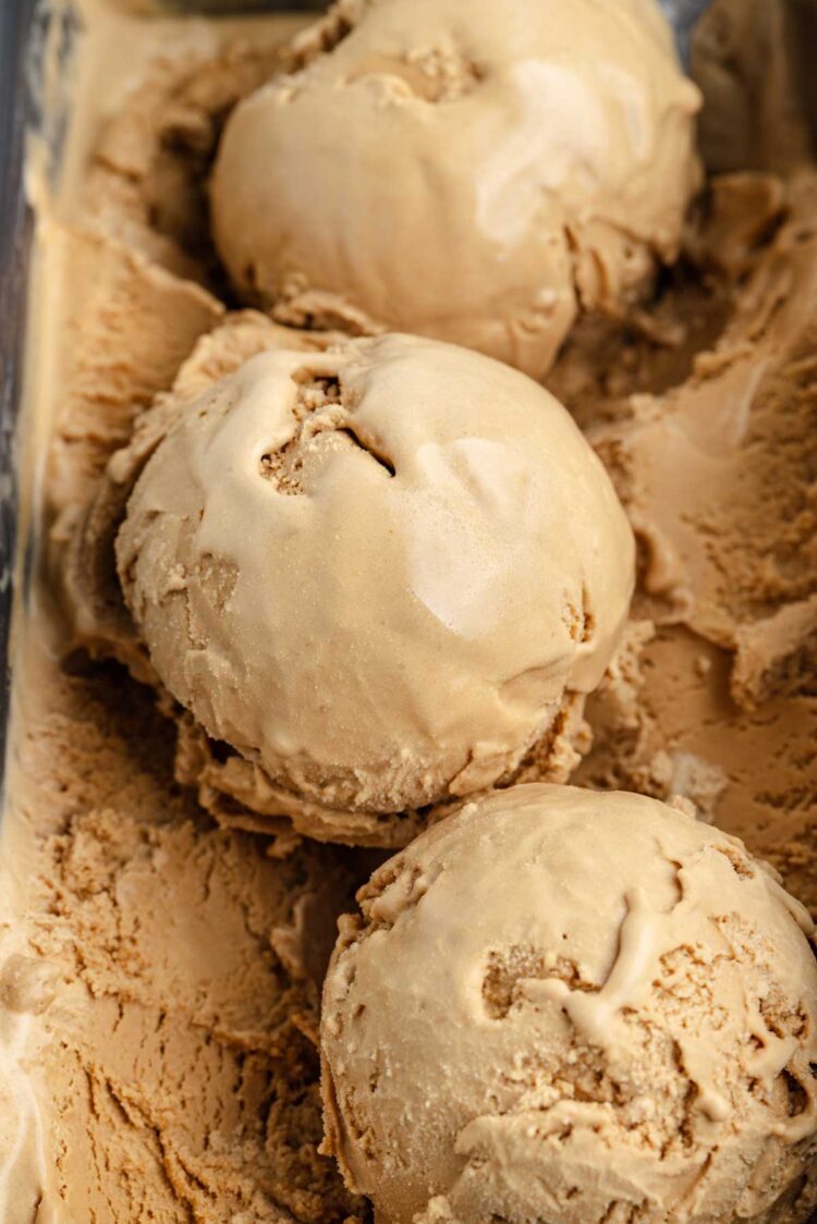 3 scoops of ice cream in a pan filled with butterscotch ice cream