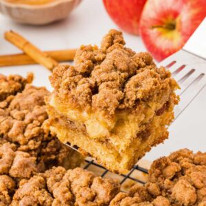 applesauce coffee cake slice being lifted on cake server with an apple in the background