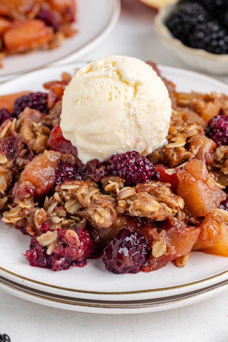 apple blackberry crumble on a white dish with ice cream on top