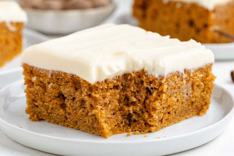 Moist sweet potato cake topped with creamy frosting, served on a white plate.